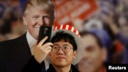 Seorang pria mengambil swafoto dengan patung karton Donald Trump di sebuah acara Kedutaan Besar AS di Seoul (9/11). (Reuters/Kim Hong-Ji)