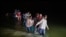Migrant families, mostly from Central American countries, wade through shallow waters after being delivered by smugglers on small inflatable rafts to U.S. soil in Roma, Texas, March 24, 2021.