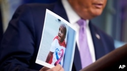 FILE - President Donald Trump holds a photo of LeGend Taliferro as he speaks at a news conference i at the White House, Aug. 13, 2020, in Washington.