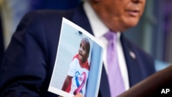 FILE - President Donald Trump holds a photo of LeGend Taliferro as he speaks at a news conference i at the White House, Aug. 13, 2020, in Washington.