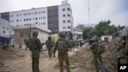 FILE — Israeli soldiers stand outside Shifa Hospital in Gaza City, November 22, 2023.