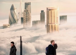 FILE - Men walk past an image of the City shrouded in fog, on a sunny spring day in London, Apr. 14, 2015.