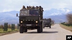 Ethnic Armenian fighters stand atop Kamaz military trucks passing through Martakert province in Azerbaijan's Armenian-administered region of Nagorno-Karabakh, April 4, 2016.