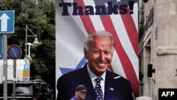 FILE - A man walks past a giant poster of US President Joe Biden in a street of Jerusalem, on October 20, 2023. Biden travelled to Israel on October 18 on a solidarity visit following Hamas attacks that have led to major Israeli reprisals on the Gaza Strip.