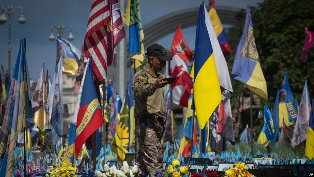 FILE - A volunteer soldier of the Ukrainian Foreign Legion takes a video at a makeshift memorial for fallen Ukrainian and foreign soldiers on Independence Square in Kyiv, Ukraine, July 23, 2024.