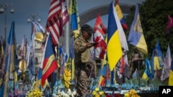 FILE - A volunteer soldier of the Ukrainian Foreign Legion takes a video at a makeshift memorial for fallen Ukrainian and foreign soldiers on Independence Square in Kyiv, Ukraine, July 23, 2024.