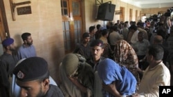 Pakistani police officers escort security officials with their faces covered, who were allegedly involved in the killing of a boy, to a police van at a local court in Karachi, June 13, 2011.