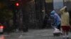 An umbrella is blown inside out as a person crosses the street during a storm in Washington, DC, on August 7, 2023.