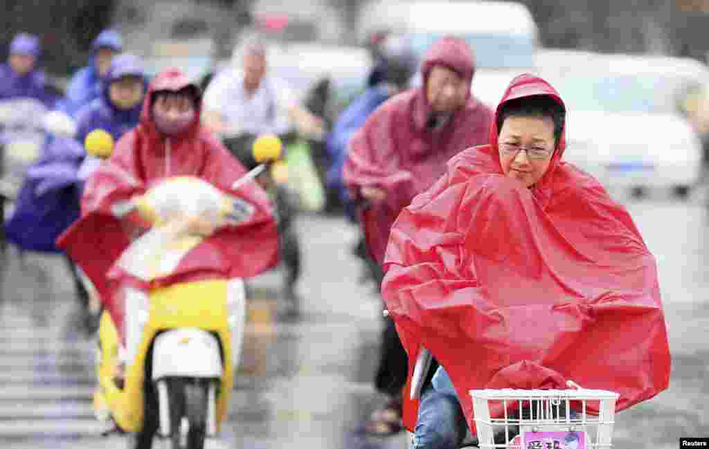 2014年7月25日，当台风马特莫袭击中国江苏省南通市时，人们骑着自行车冒着大风和强降雨而行进。