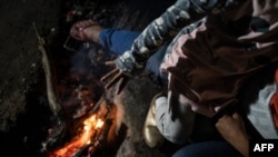 Una niña calienta su mano sobre una fogata en el campamento de su familia en el Parque Chamizal, en Ciudad Juárez, México, el 10 de diciembre de 2019, mientras esperan por asilo. 