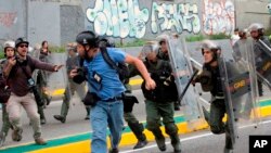 El reportero fotográfico de Reuters, Marco Bello, corre mientras los soldados de la Guardia Nacional venezolana lo persiguen durante una protesta frente a la Corte Suprema en Caracas, Venezuela, el 31 de marzo de 2017. 