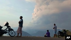 Residents watch as Mount Lewotobi Laki Laki volcano spews volcanic materials during an eruption in East Flores, Indonesia, Nov, 9, 2024.