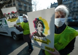 A human rights activist stages a protest with a placard that depicts women's rights campaigner Yasaman Aryani on a square near the Iranian embassy during Women' s Day in Paris, March 8, 2021.