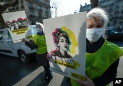 A human rights activist stages a protest with a placard that depicts women's rights campaigner Yasaman Aryani on a square near the Iranian embassy during Women' s Day in Paris, March 8, 2021.