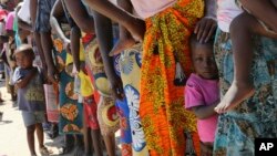 Women and children wait in a queue for oral cholera vaccinations, at a camp for displaced survivors of cyclone Idai in Beira, Mozambique, Wednesday, April 3, 2019. 