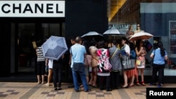 Mainland Chinese tourists wait outside a Chanel store at Hong Kong's Tsim Sha Tsui shopping district, Oct. 1, 2014, with part of it being blocked by protesters.