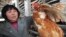 A farmer holds a chicken as she poses for a photograph at a hennery in Beifan village of Zouping county, Shandong province, China, April 1, 2013.