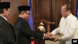 Ketua Front Pembebasan Islam Moro Haji Murad Ebrahim (tengah) dan Presiden Filipina Benigno Aquino usai menandatangani kesepakatan damai di Manila (15/10).