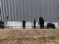 FILE - President Donald Trump signs a plaque that bears his name on the 450th mile of the border wall in Texas, January 12, 2021.