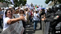 A woman confronts police officers as employees of the Judiciary, who are on an indefinite strike, protest in front of the Supreme Court of Justice in Mexico City on August 25, 2024.