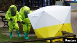 FILE - The forensic tent, covering the bench where Sergei Skripal and his daughter Yulia were found, is repositioned by officials in protective suits in the center of Salisbury, Britain, March 8, 2018.