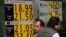 People walk past a board displaying the exchange rate for Mexican peso against the U.S. dollar and the euro in a Bank in Mexico City, Mexico, Nov. 15, 2016. 