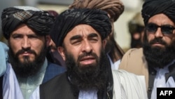 FILE - Taliban spokesman Zabihullah Mujahid, center, addresses a media conference at the airport in Kabul on Aug. 31, 2021.
