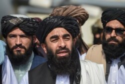 Taliban spokesman Zabihullah Mujahid, center, addresses a media conference at the airport in Kabul on Aug. 31, 2021.