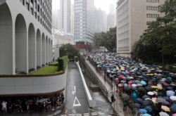 FILE - Pro-democracy protesters walk with umbrellas in the rain in Hong Kong, Aug. 31, 2019. The crowd alternated between singing hymns and chanting slogans of the pro-democracy movement.
