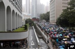 FILE - Pro-democracy protesters walk with umbrellas in the rain in Hong Kong, Aug. 31, 2019. The crowd alternated between singing hymns and chanting slogans of the pro-democracy movement.