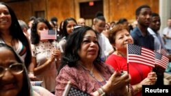 New citizens stand during a U.S. Citizenship and Immigration Services (USCIS) naturalization ceremony at the New York Public Library in Manhattan, New York, July 3, 2018. 