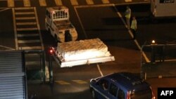 Police officers escort an airport vehicle transporting what is believed to be debris from a Boeing 777 plane that washed up on Reunion Island, at Roland Garros airport in Saint-Marie, Reunion Island, July 31, 2015.