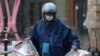 Repartidor con mascarilla entrega comida en medio de nevadas, luego de un brote del nuevo coronavirus en el país, en una zona comercial el Día de San Valentín en Beijing, China, 14 de febrero de 2020.