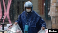 Repartidor con mascarilla entrega comida en medio de nevadas, luego de un brote del nuevo coronavirus en el país, en una zona comercial el Día de San Valentín en Beijing, China, 14 de febrero de 2020.