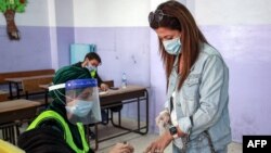 A voter, mask-clad due to the coronavirus pandemic, dips her finger in ink after voting at a polling station in Jordan's capital Amman, Nov. 10, 2020.