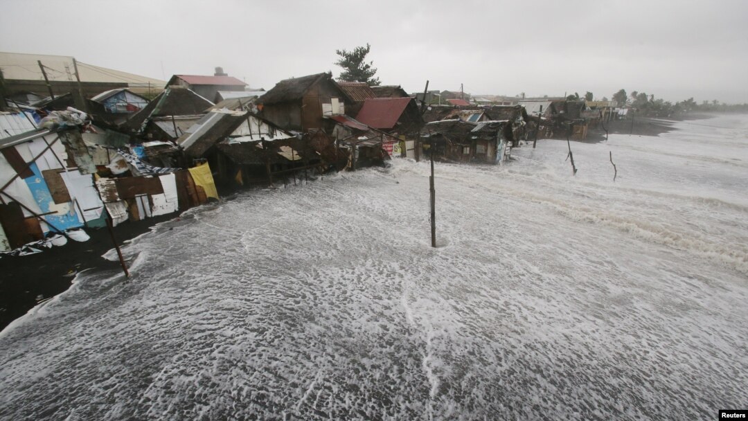 Ombak kuat menghantam rumah-rumah di pinggir pantai akibat Topan Hagupit yang melanda Legazpi, provinsi Albay, Filipina, 7 Desember 2014. 