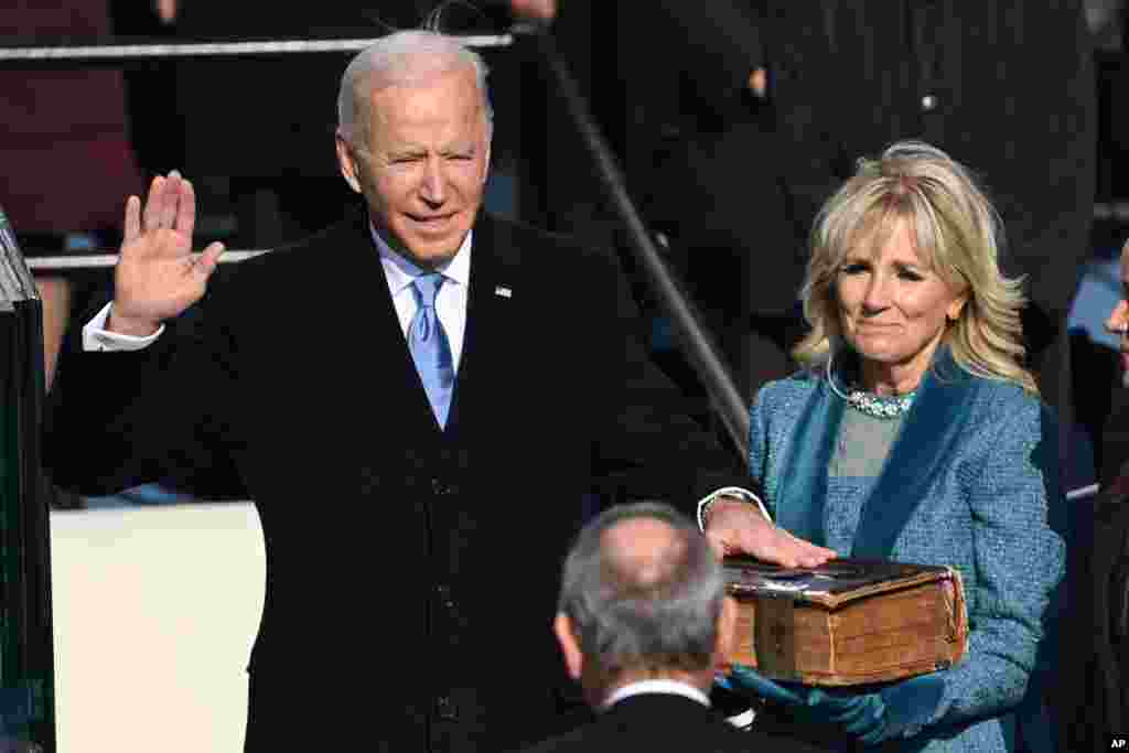 Joe Biden is sworn in as the 46th president of the United States by Chief Justice John Roberts as Jill Biden holds the Bible during the 59th Presidential Inauguration at the U.S. Capitol in Washington.