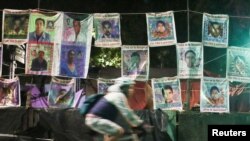 Una persona pasa junto a una pared con fotos de algunos de los 43 estudiantes que desaparecieron del Colegio Rural de Maestros de Ayotzinapa. Tomada en Ciudad de México, el 19 de agosto de 2022.