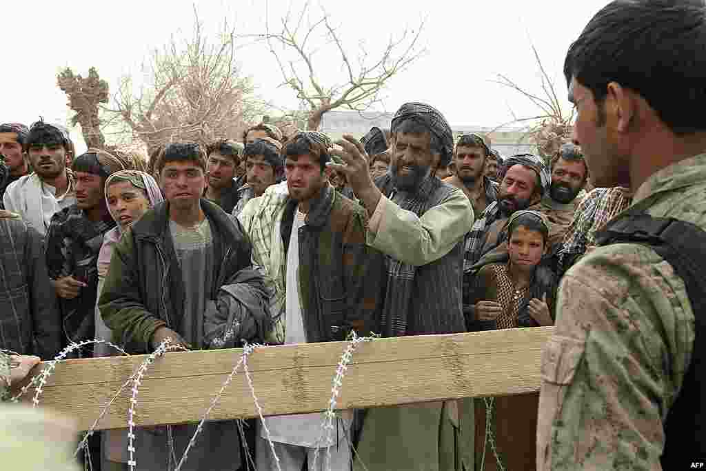 An Afghan soldier speaks to civilians gathered outside a military base in Panjwai. (AP)