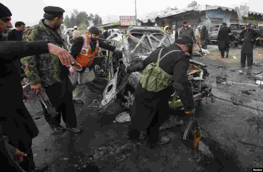 Police officers try to move a car, which was damaged during a bomb attack at Fauji Market in Peshawar December 17, 2012. The blast in the market in northwest Pakistan on Monday killed at least 15 people, a security official said. The official said at leas