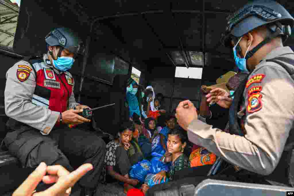 Police officers escort Rohingya refugees after rescuing them from a boat after a week anchored ashore off the coast of Labuhan Haji in Southern Aceh province.