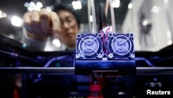 FILE - A staff member of Nihonbinary demonstrates their 3D printer MakerBot Replicator 2X as it prints an Acrylonitrile butadiene styrene pylon during the International Robot Exhibition 2013 in Tokyo, Nov. 8, 2013. 