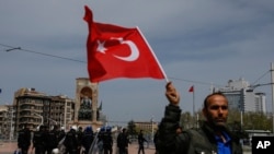 Un sympathisant du principal parti d'opposition, le Parti populaire républicain (CHP), brandit un drapeau turque alors que les manifestants se rassemblent pour un sit-in sur la place Taksim, au centre d'Istanbul, lundi 16 avril 2018.