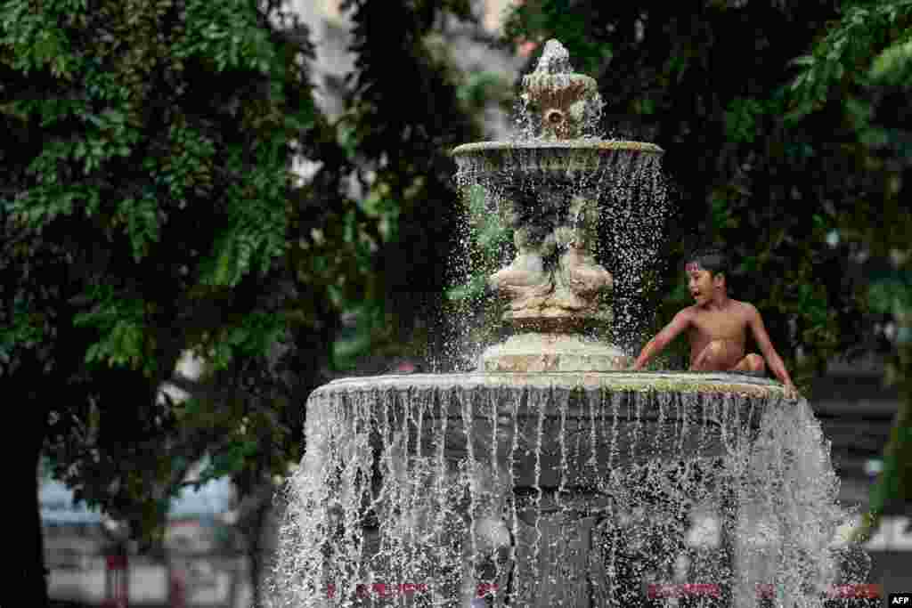 A boy plays in a water fountain at a public park in Manila, Philippines.