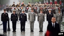 FILE - French generals and admirals stand guard behind French President (front right) at the tomb of the unknown soldier under the Arc de Triomphe landmark on top of the Champs Elysees avenue on May 8, 2019 in Paris. 