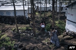 FILE - Two girls walk around the Rusayo IDP camp, home to tens of thousands of war-displaced people, on the outskirts of Goma, in the East of the Democratic Republic of Congo, on October 2, 2023.