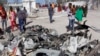 Des Somaliens passent devant des débris après un attentat suicide à la voiture piégée contre un bâtiment du gouvernement dans la capitale Mogadiscio, en Somalie, samedi 23 mars 2019. Des hommes armés d'Al-Shabab ont pris d'assaut le bâtiment du gouvernement après l'attentat à la 
