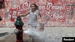 A girl cools off from the heat in water from an open fire hydrant in the Washington Heights section of upper Manhattan in New York City, New York, U.S., July 19, 2019. (REUTERS/Mike Segar)