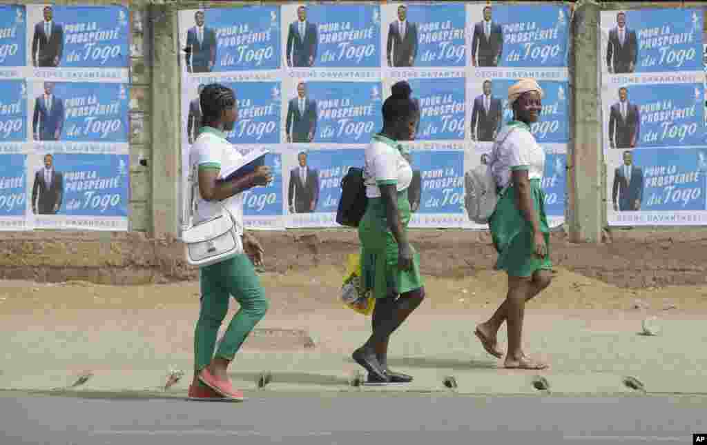 Anak-anak sekolah berjalan melewati poster-poster kampanye pemilihan kembali Presiden Togo Faure Gnassingbe, di jalan di Lome, Togo.&nbsp;Faure Gnassingbe memenangkan Pilpres dan akan menjadi Presiden untuk masa jabatan ke-4 sejak 2005.&nbsp;