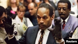 FILE - O.J. Simpson, wearing the blood stained gloves found by Los Angeles Police and entered into evidence in Simpson's murder trial, displays his hands to the jury at the request of prosecutor Christopher Darden in this file photograph from June 15, 1995.